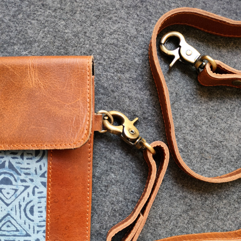 Brown leather bag with a strap on a textured gray surface
