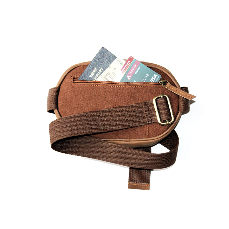 Brown crossbody bag with a strap, containing some items on a white background