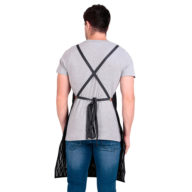 Person wearing a black apron with cross straps over a gray shirt on a white background