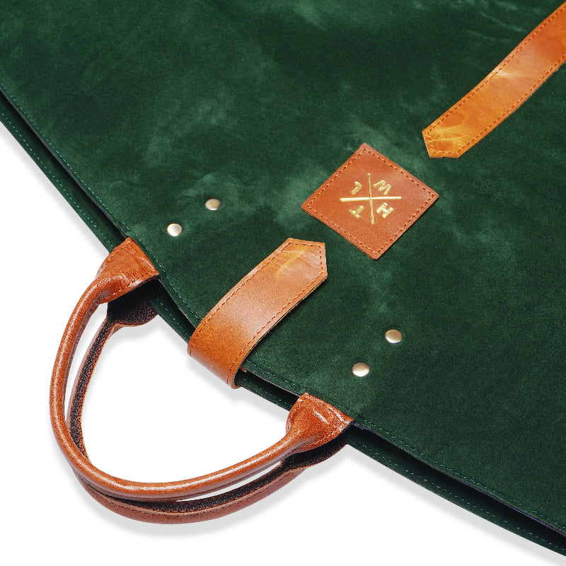 Green leather blazer cover with brown leather handles and zipper, stylish and durable garment bag for suits and coats.