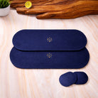 Two navy blue heating placemat and coaster  with a logo on a light wooden surface.