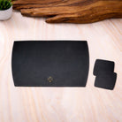 Black leather tray with a logo and two coasters on a wooden surface