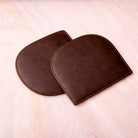 Two brown leather coasters on a light beige surface