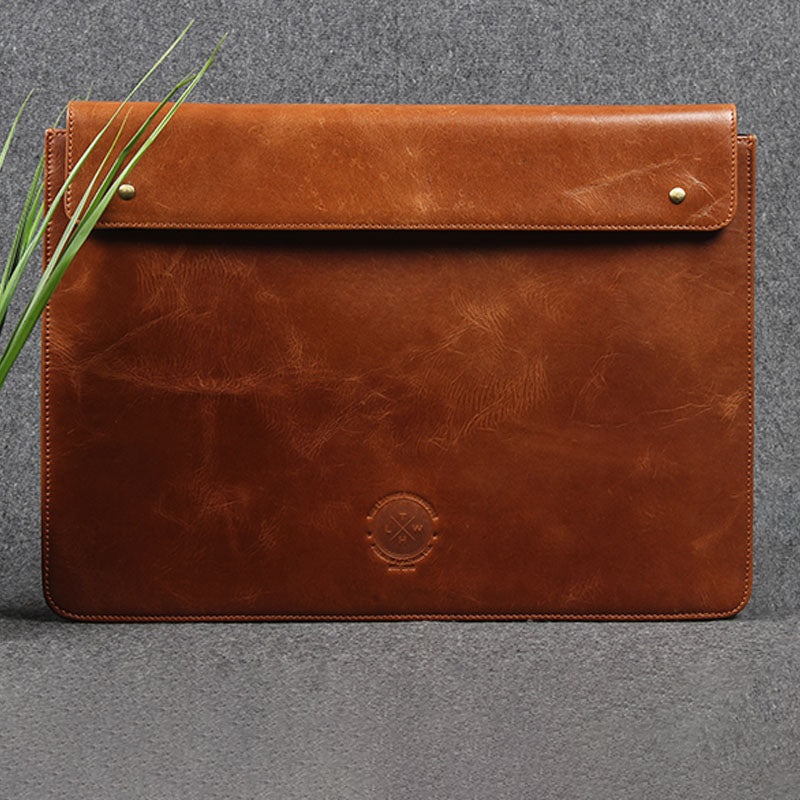 Handcrafted tan brown leather laptop sleeve with flap closure, minimalist design, and natural grain finish.
