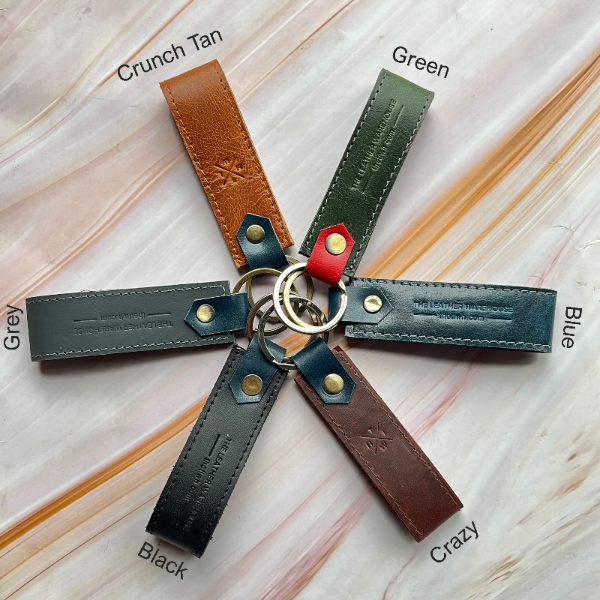 Keychain with leather straps in various colors on a light wooden surface
