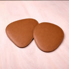 Pair of brown leather coasters on a light pink surface