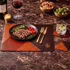 Dinner setup with steak, wine, and appetizers on a marble table. with placemat and coaster