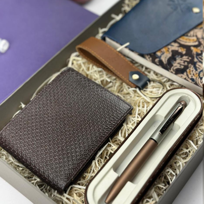 Brown leather wallet and pen set in a gift box with decorative elements.