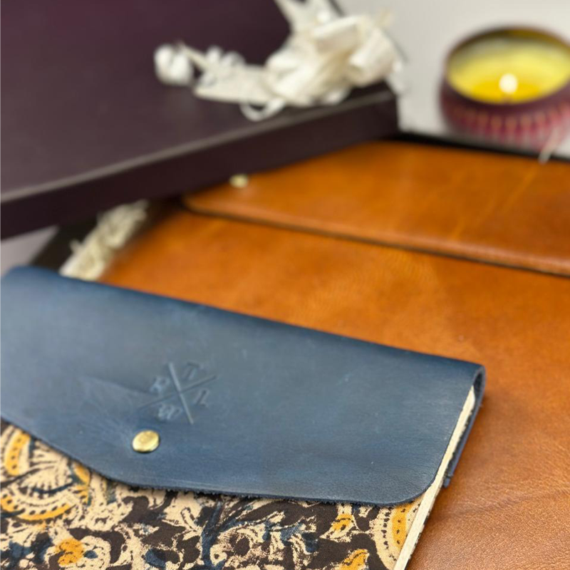 Blue leather clutch with floral pattern on a wooden surface
