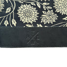 Floral patterned fabric with a leather strap and branding on a white background