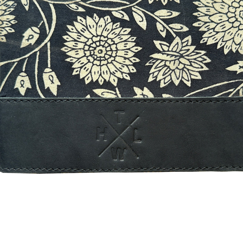 Floral patterned fabric with a leather strap and branding on a white background