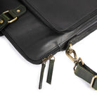Black leather bag with green strap and gold hardware on a white background