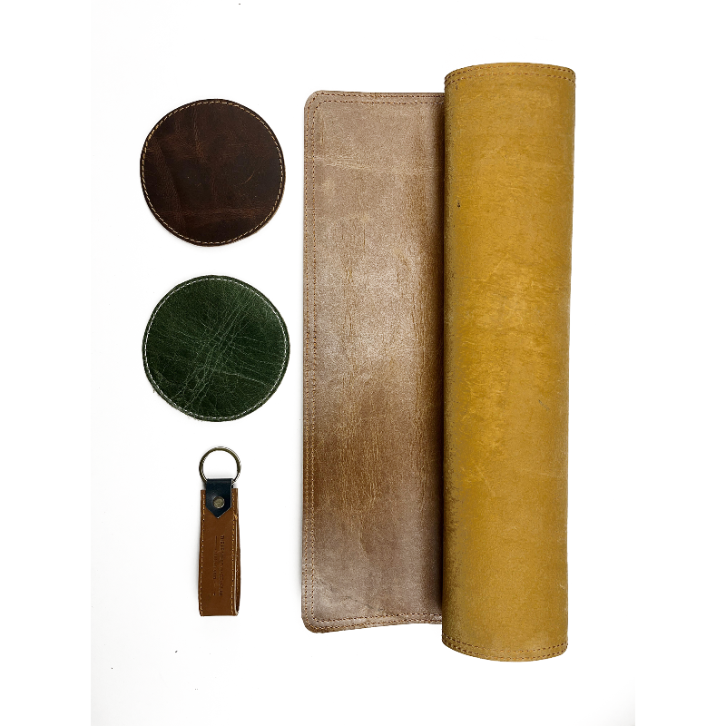 Set of leather items including a wallet, keychain, and coasters on a white background