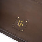 Chocolate Brown leather product with a gold logo on a white background