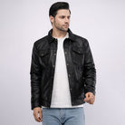 Man wearing a black leather jacket over a white shirt on a light gray background