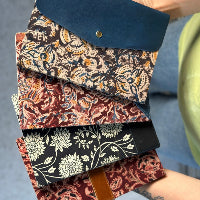 Stack of patterned books held by a person with a blurred background