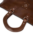 Brown leather bag with handle and visible brand logo on a white background