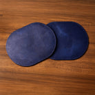 Two blue oval coasters on a wooden surface