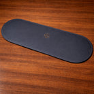 Black leather placemat with a logo on a wooden surface