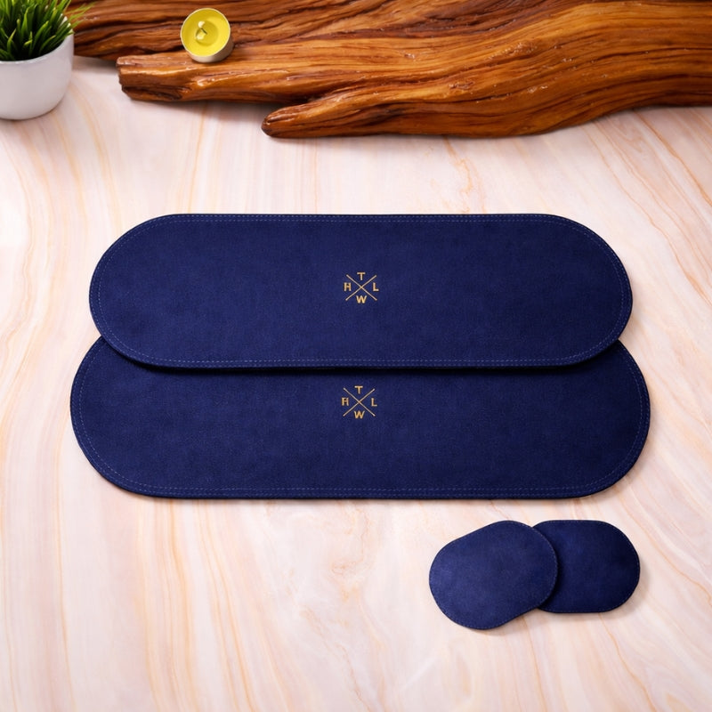 Two navy blue heating placemat and coaster  with a logo on a light wooden surface.