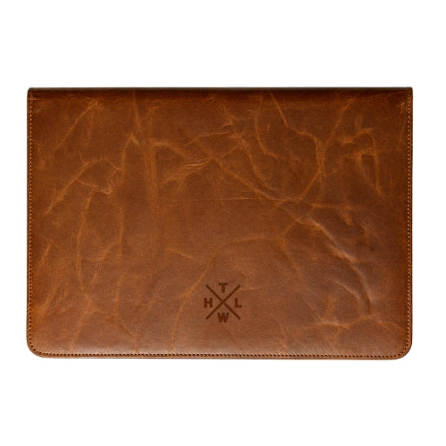A brown textured leather sleeve or cover with visible grain and a debossed cross logo with initials at the bottom center, shown flat against a plain white background.