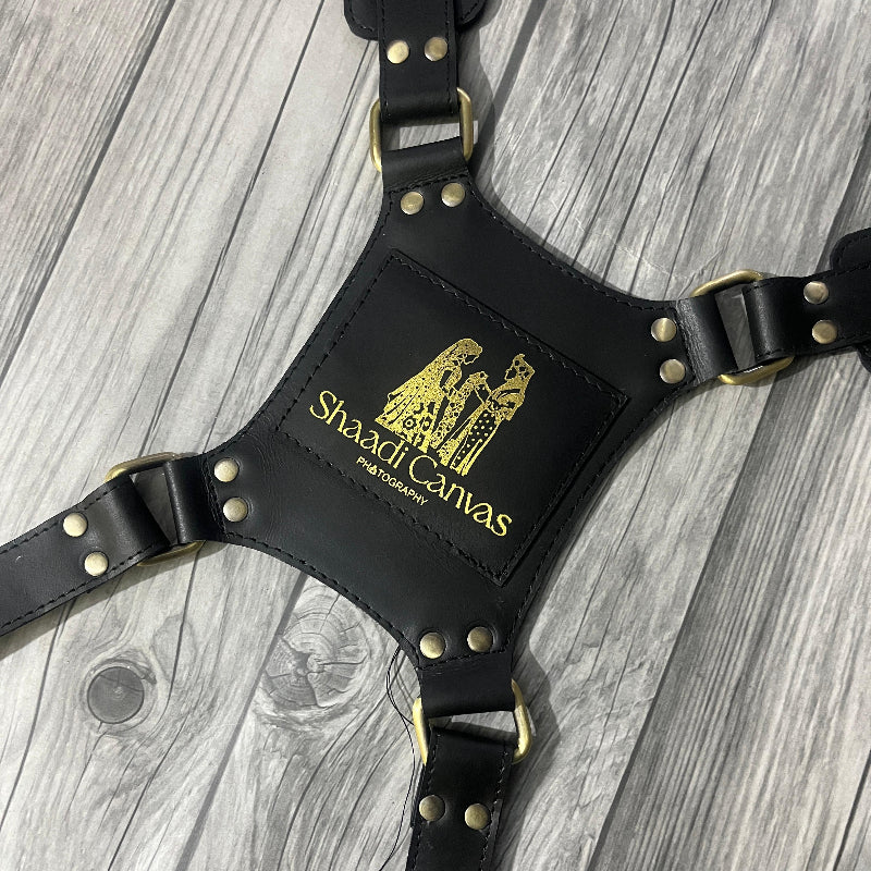 Black leather harness with gold studs on a wooden surface, featuring 'Shardt Canvas' branding.