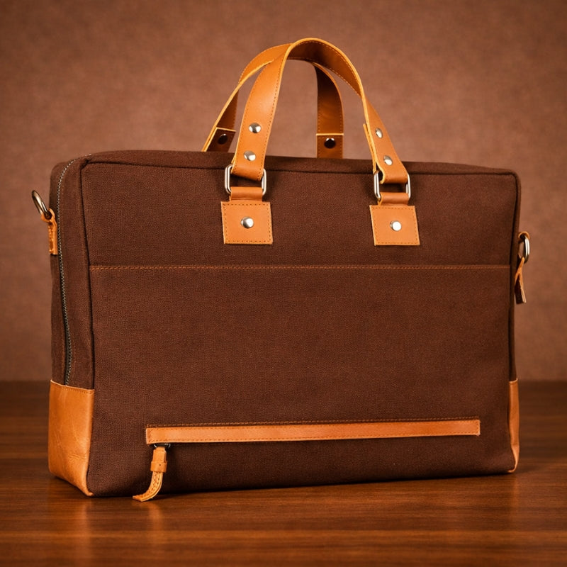 Brown canvas & leather briefcase with tan accents on a wooden surface