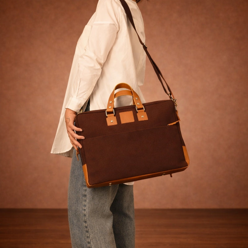 Person holding a brown canvas & leather briefcase against a brown background