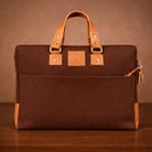 Brown canvas briefcase with tan leather handle and trim on a brown background