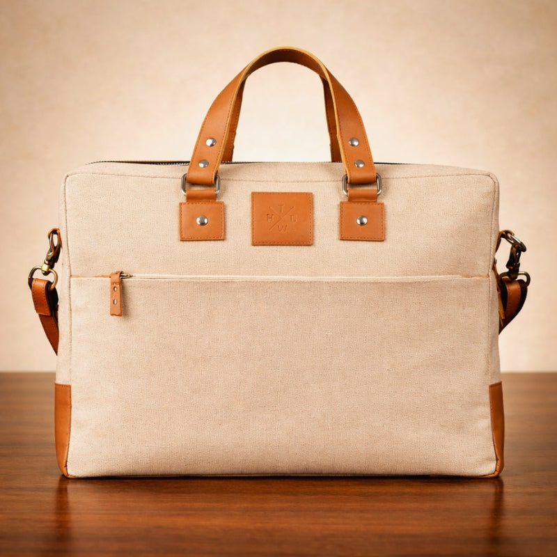 Beige canvas laptop bag with brown leather straps on a wooden surface
