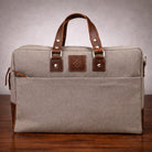 Gray bag with brown canvas & leather straps on a wooden surface