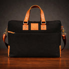 Black bag canvas with brown leather straps on a wooden surface