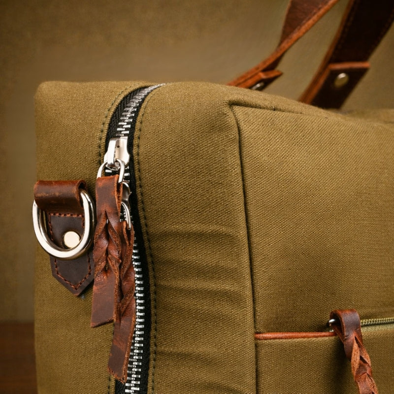 Close-up of a green canvas bag with leather accents and zipper