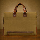 Green canvas briefcase with brown leather straps on a wooden surface and brown background