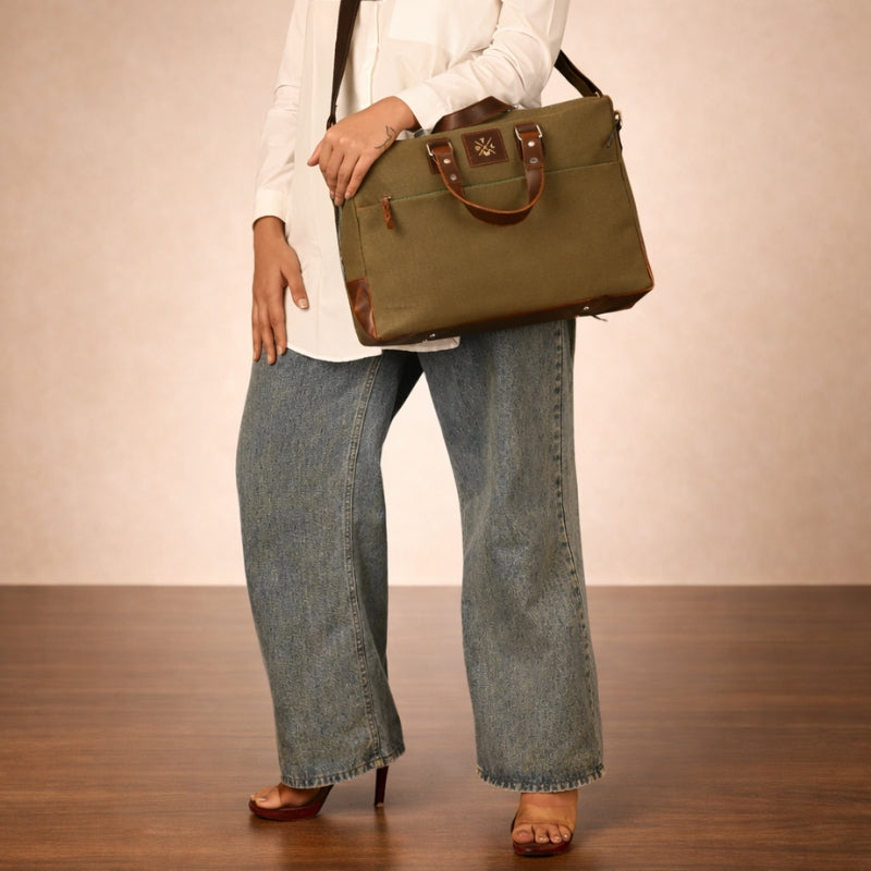 Person holding a green canvas handbag with a plain background