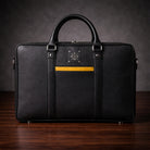 Black leather briefcase with gold accent on a wooden surface and dark background
