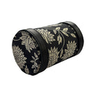 Black cylindrical container with gold floral pattern on a white background