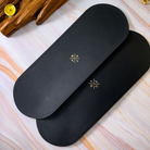 Black placemat with gold logo on a light wooden surface