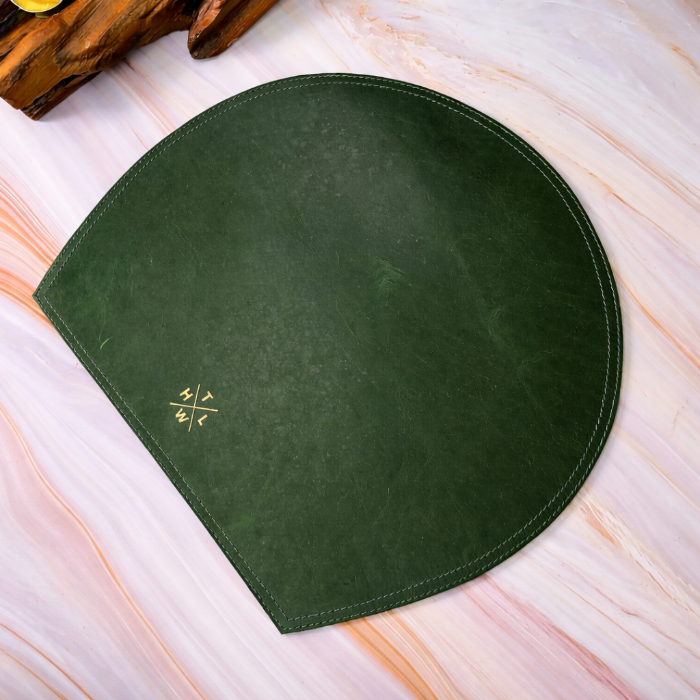 Green round placemat with a logo on a marble surface