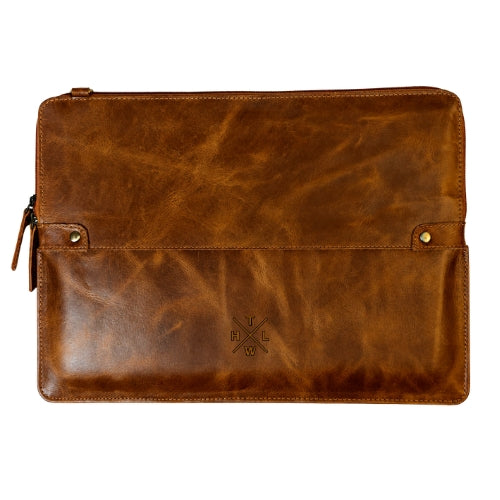 A brown distressed leather laptop sleeve with a front flap pocket, brass-tone snap buttons, and a small embossed cross logo on a white background.