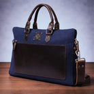 Blue canvas handbag with brown leather accents on a wooden surface