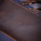 Close-up of a brown leather bag with a blue canvas fabric base