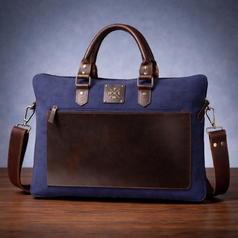 Blue and brown canvas & leather bag on a wooden surface with a blue gradient background