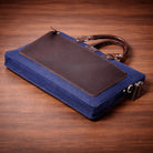 canvas & leather blue laptop bag on wooden surface.