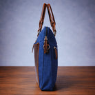 Blue canvas laptop bag with side view on a wooden surface with a blue background