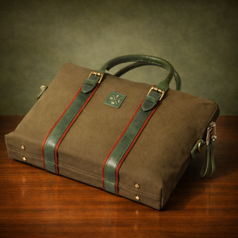 Brown canvas & leather briefcase with green straps on a wooden surface