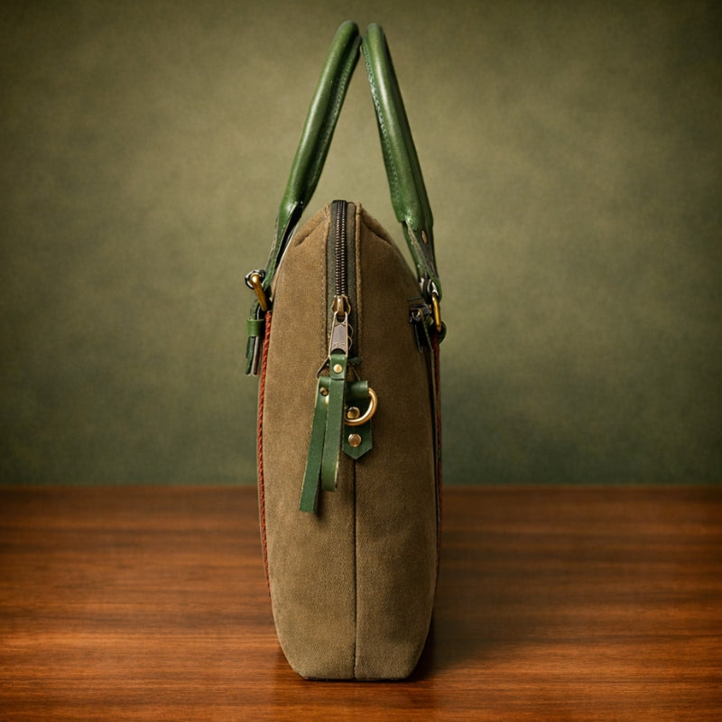 Brown canvas & leather bag with green handles on a wooden surface and brown background