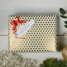 Gift box with gold polka dot pattern, red ribbon, and white card on a light wooden surface.