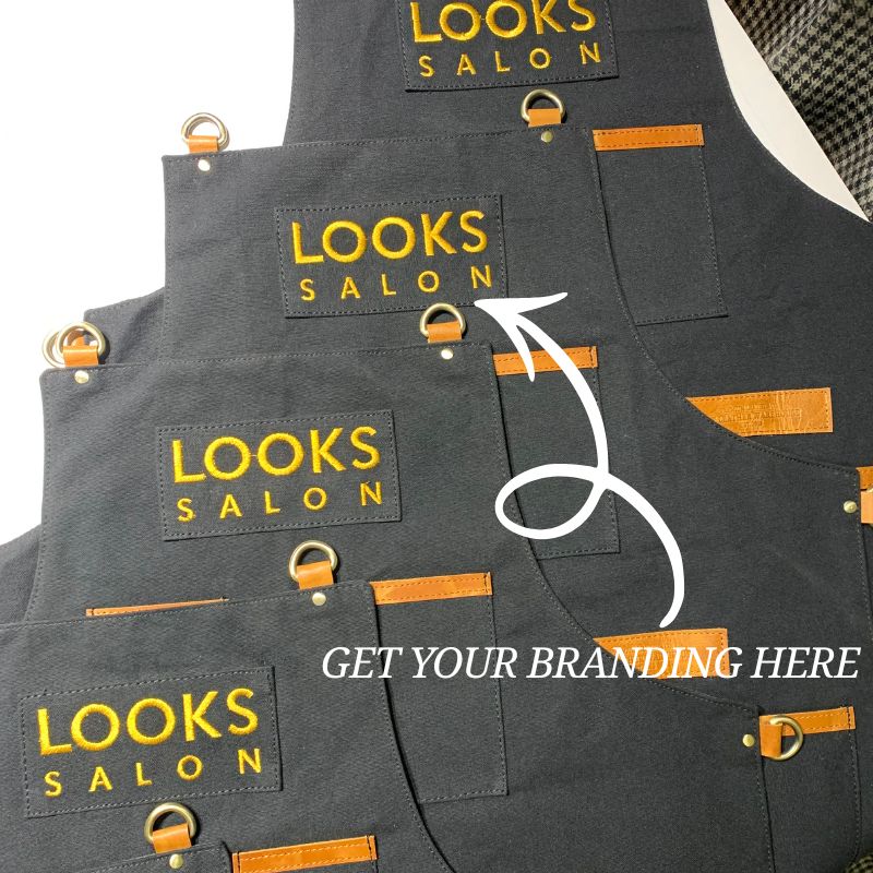 Stack of gray aprons with 'LOOKS SALON' branding on a white background