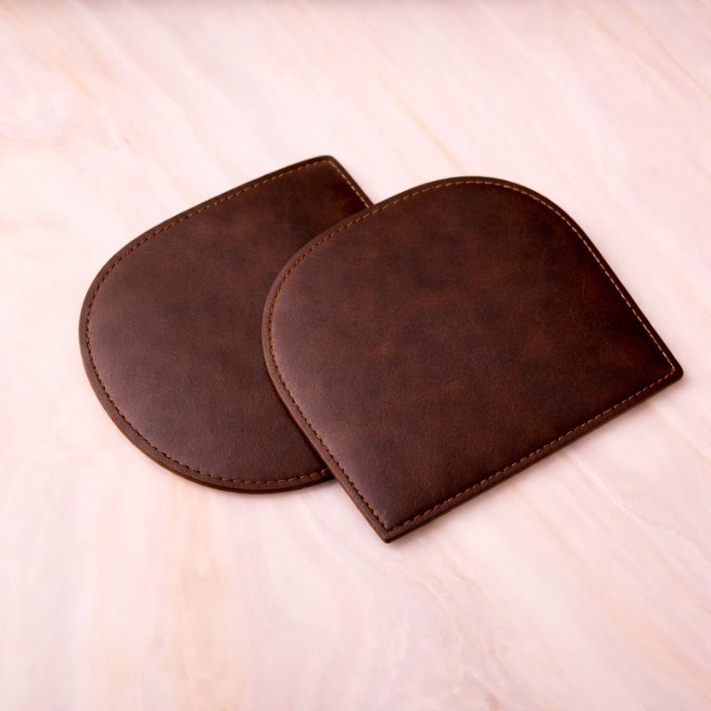 Two brown leather coasters on a light beige surface